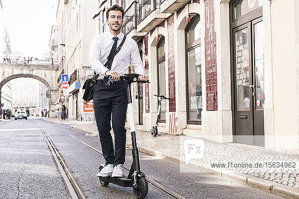 Young businessman riding e-scooter in the city  Lisbon  Portugal