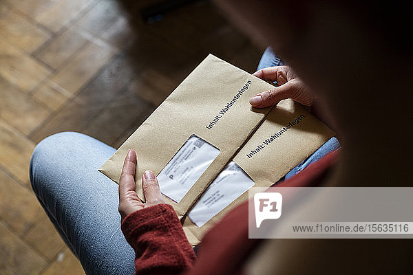Weibliche Wählerin hält Dokumente für die Briefwahl in den Händen