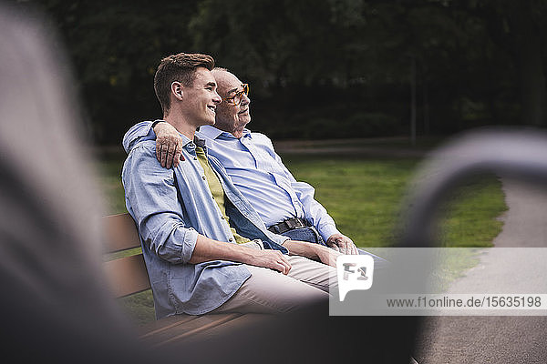 Senior man and grandson relaxing together on a park bench