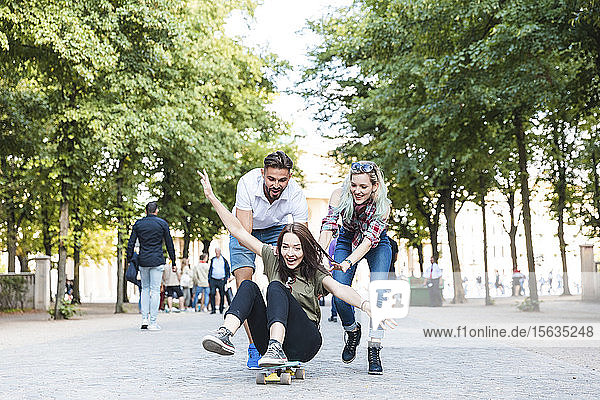 Gruppe von drei Freunden amüsiert sich mit Skateboard