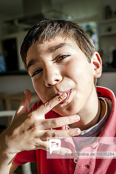 Portrait of boy at home licking his finger