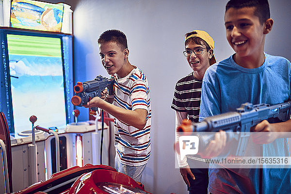 Teenage friends shooting with guns in an amusement arcade