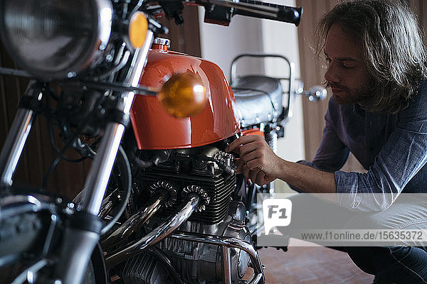 Junger Mann überprüft sein in der Garage geparktes Oldtimer-Motorrad