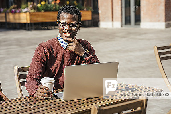 Junger Mann benutzt Laptop in einem Café und trinkt Kaffee