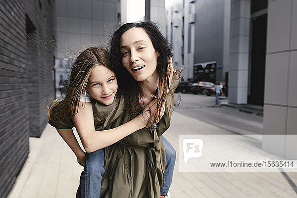 Portrait of mother giving her daughter a piggyback ride
