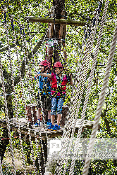 Boy and girl on a high rope course in forest
