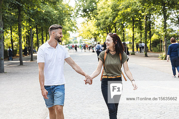 Happy young couple walking hand in hand in a park