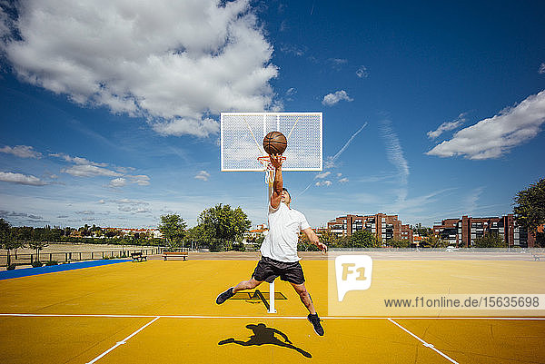 Mann spielt Basketball auf gelbem Platz  Dunking