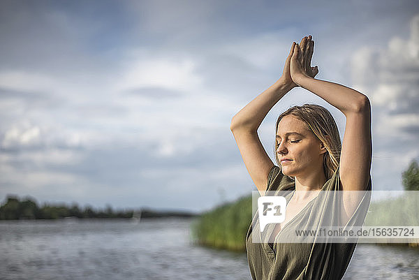 Frau meditiert an einem See