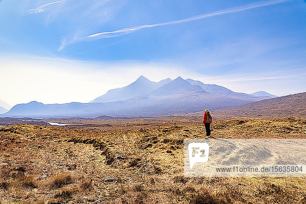 Mature woman standing on land while Cuillin mountains in background Isle of Skye Highlands Scotland UK