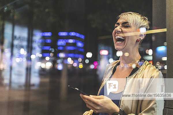 Porträt einer lachenden blonden Frau  die nachts mit dem Handy telefoniert  Berlin  Deutschland