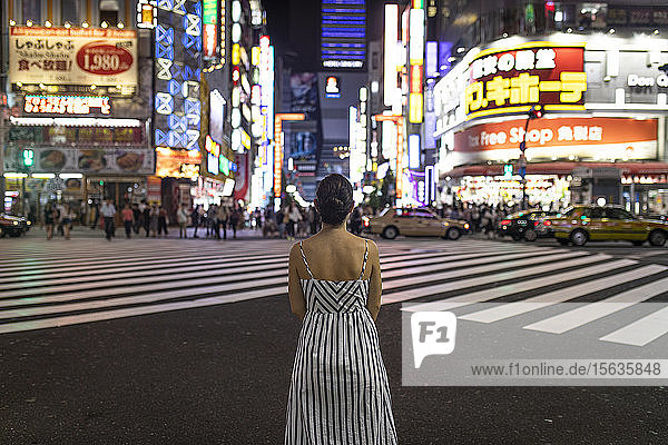 Junge Frau  die nachts nachdenkt  Menschen  die die Shinjuku-Straße überqueren  Tokio  Japan