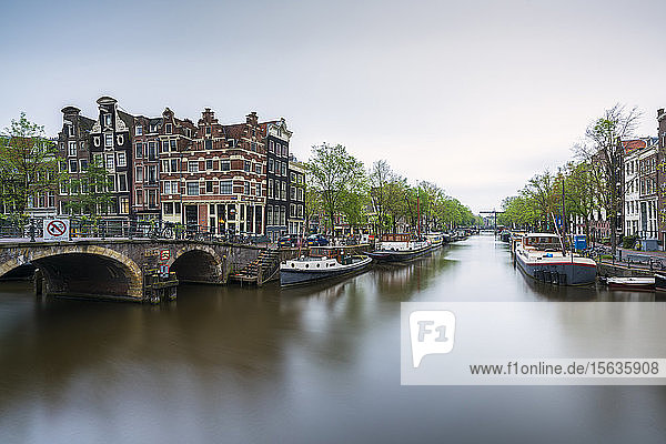 Niederlande  Amsterdam  Bogenbrücke über den Stadtkanal mit im Hintergrund vertäuten Booten