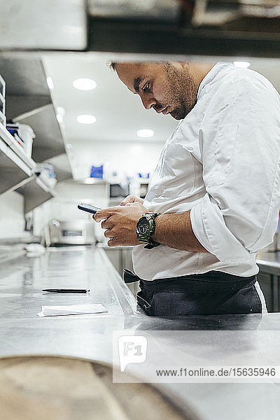 Küchenchef mit Smartphone in der Küche
