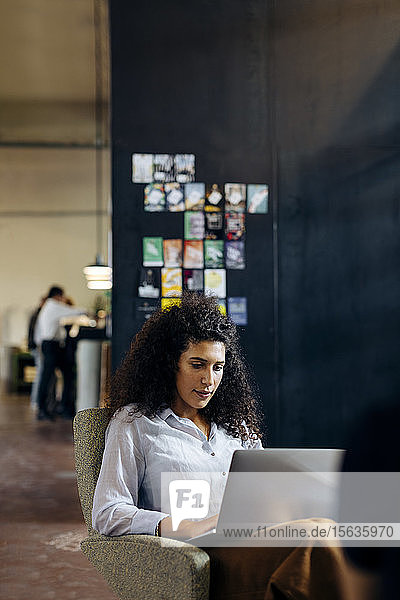 Junge Geschäftsfrau benutzt Laptop im Loft-Büro