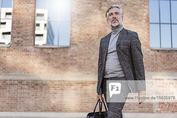 Fashionable mature businessman with bag on the go in the city