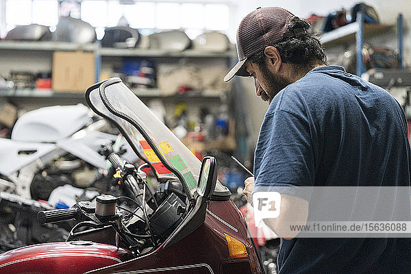 Mechaniker in einer Reparaturwerkstatt  der ein Motorrad repariert