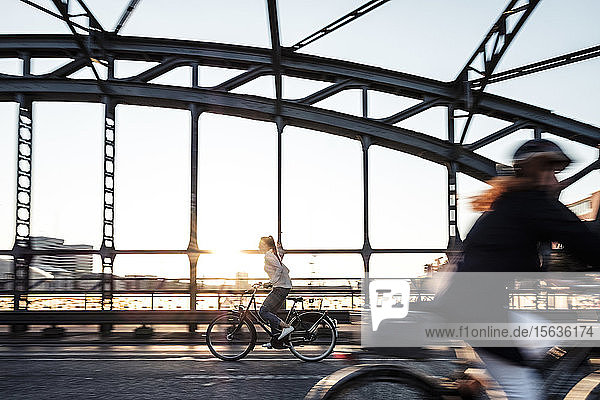 Junger Radfahrer auf einer Brücke bei Sonnenuntergang