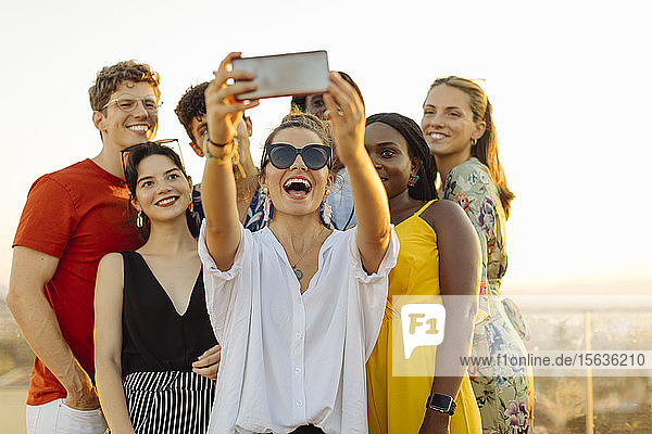 Gruppe glücklicher multiethnischer Freunde  die sich während einer Party am Abend ein Selfie gönnt