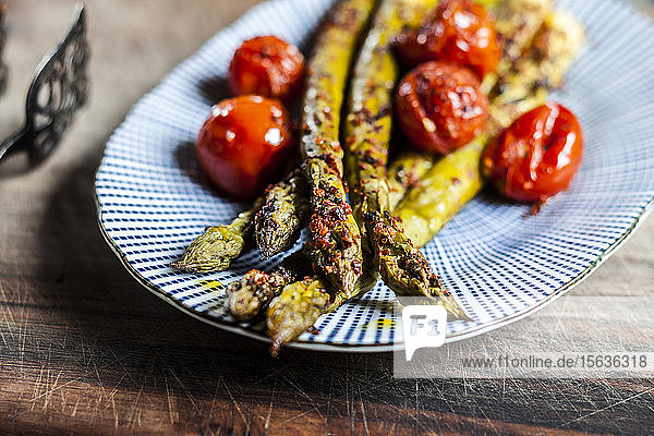 Gegrillter grüner Spargel mit Kirschtomaten auf einem Teller