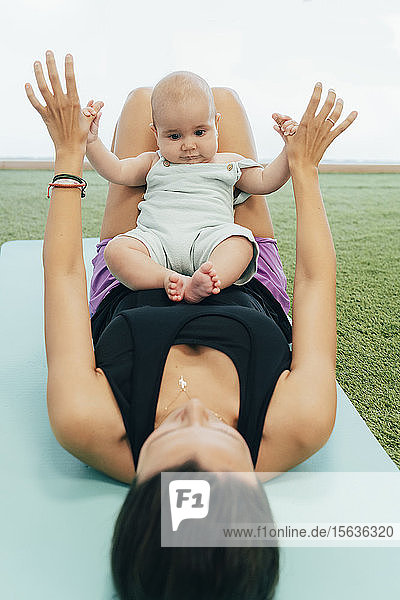 Junge Mutter und Baby üben auf der Yogamatte