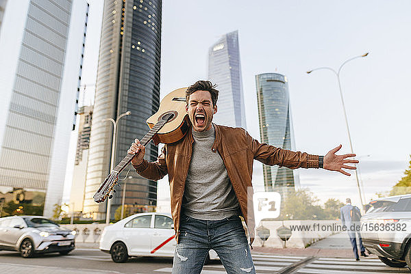 Portrait of screaming man with guitar in the city Madrid Spain