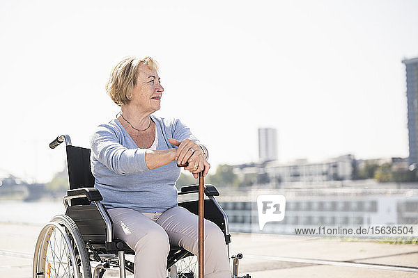 Ältere Frau im Rollstuhl sitzend  mit Gehstock