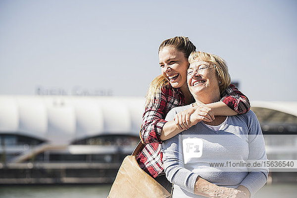 Young woman embracing her smiling grandmother sitting in wheelchair