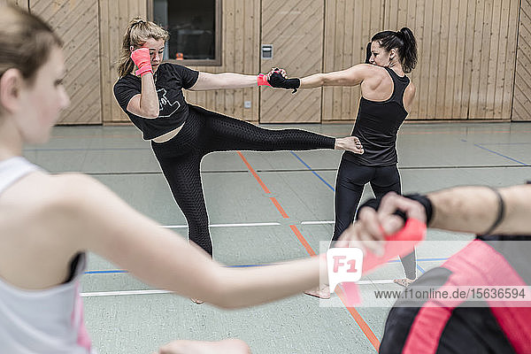 Female kickboxers practising in sports hall