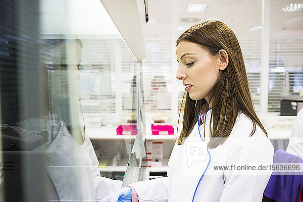 Seitenansicht einer Wissenschaftlerin in weißer Kleidung  die in einem modernen Labor arbeitet