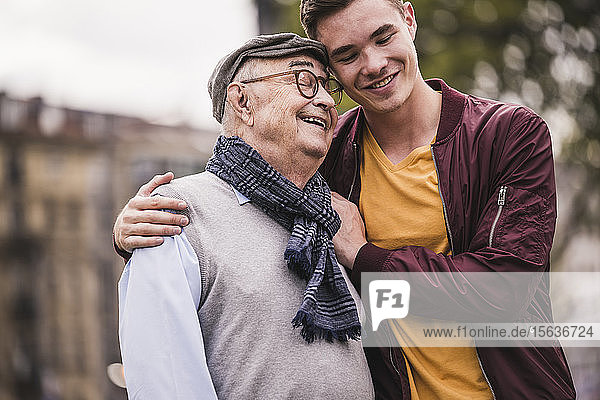 Happy senior man head to head with his adult grandson outdoors