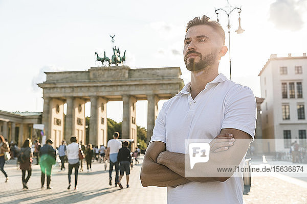 Porträt eines jungen Mannes  der vor dem Brandenburger Tor im Gegenlicht steht  Berlin  Deutschland