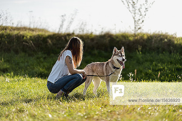 Young woman with her dog on a meadow