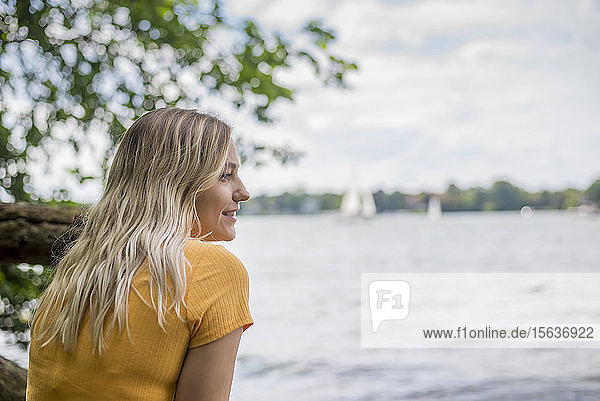 Lächelnde Frau sitzt am Seeufer