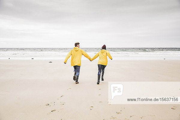 Junge Frau in gelben Regenjacken und Strandspaziergang  Bretagne  Frankreich