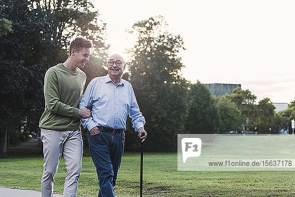 Young man assisting his grandfather walking in a park