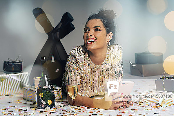 Porträt einer jungen Frau  die für eine Party gekleidet ist und Weihnachten mit Geschenken und Champagner feiert