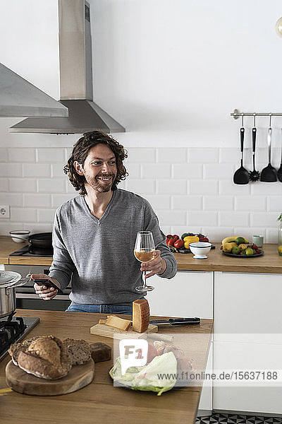 Lächelnder Mann mit Handy in der Küche zu Hause