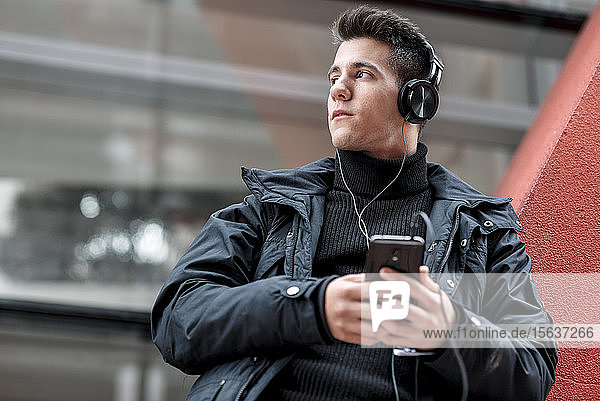 Young man with smartphone and headphones listening to music