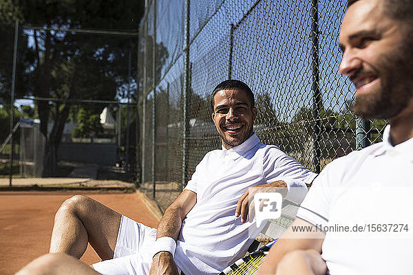 Tennisspieler sitzen auf einer Bank und unterhalten sich in der Pause