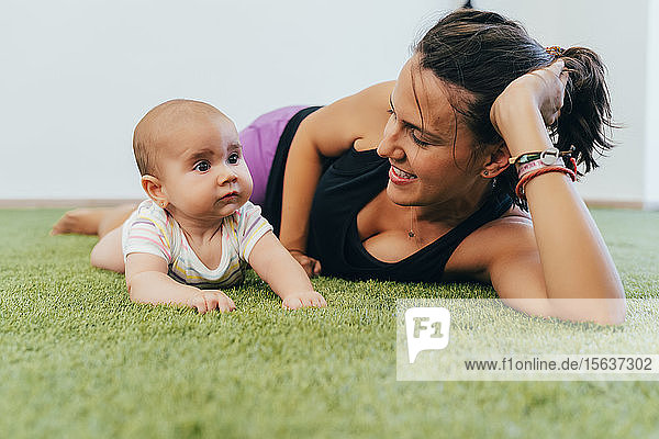 Junge Mutter und Baby trainieren auf grünem Teppich