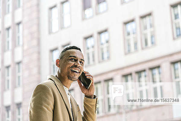Porträt eines lachenden Geschäftsmannes am Telefon in der Stadt