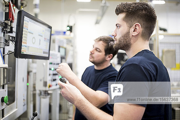 Zwei Männer arbeiten in einer modernen Fabrik und bedienen gemeinsam eine Maschine