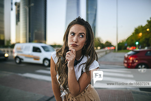 Young woman with doubtful face  skyscrapers in the background