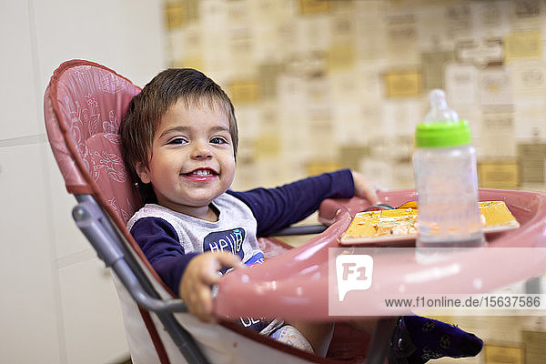 Porträt eines glücklichen kleinen Jungen auf einem Hochstuhl sitzend