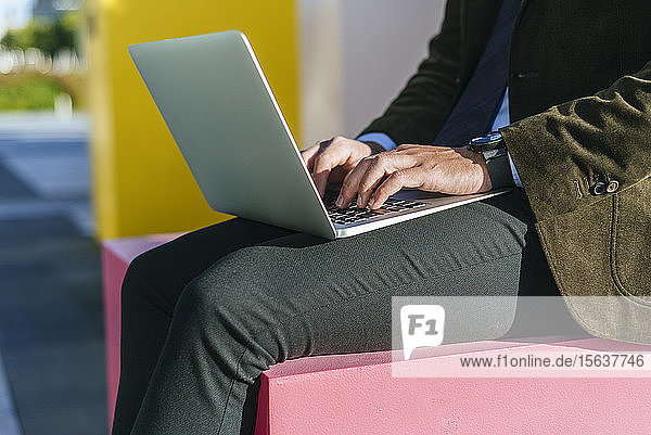 Close-up of businessman's hands using laptop outside