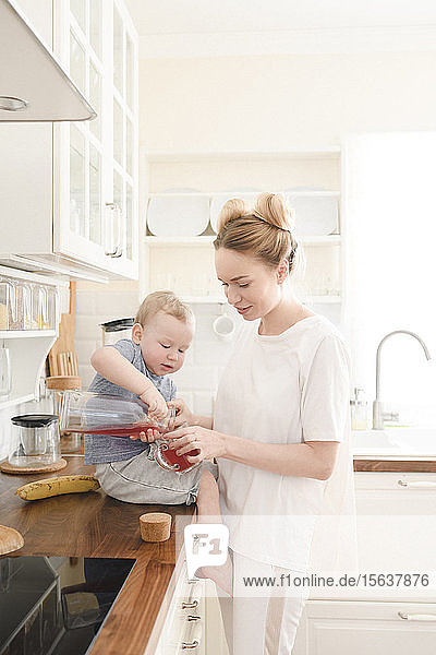 Mutter mit ihrem kleinen Jungen mit Saft in der Küche