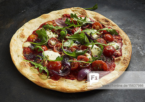 Nahaufnahme einer Pizza mit Tomaten  Zwiebeln  Mozzarella und Basilikum