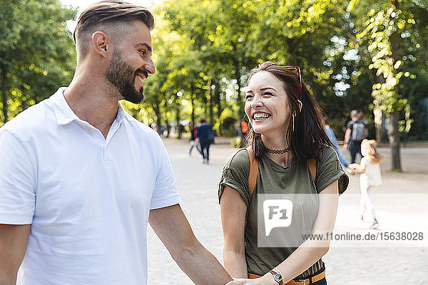 Portrait of happy young woman walking hand in hand with her boyfriend in a park