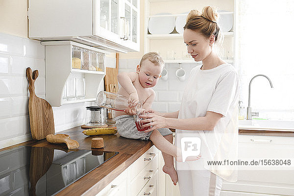 Mother with her little boy with juice in the kitchen